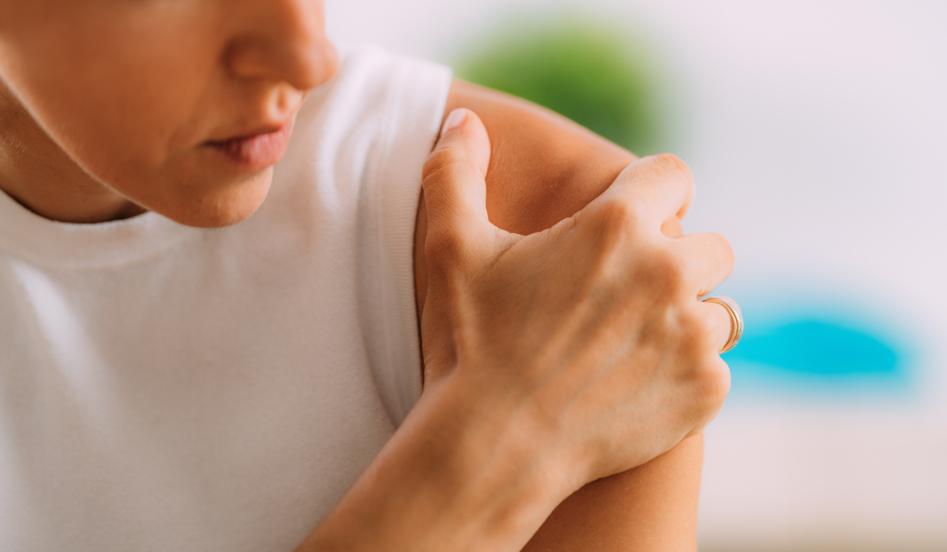 A woman holds her shoulder indicating she has pain in the area.