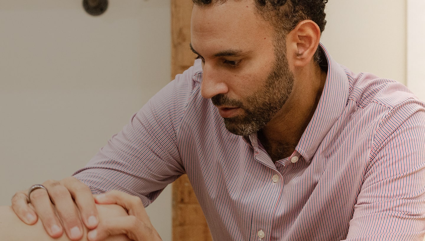 Dr. Stephen Matta gently holds a patient's knee during a medical consultation.