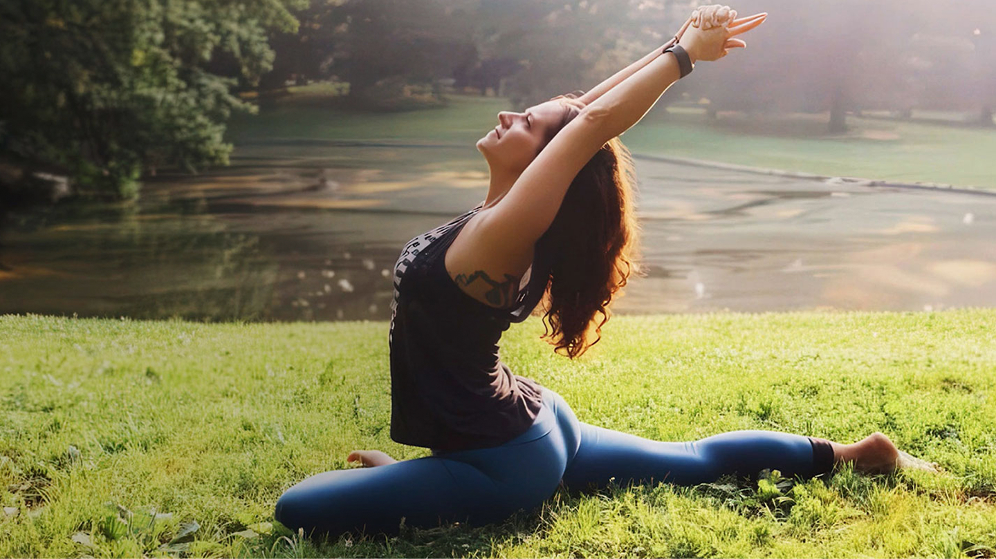 A woman practicing yoga on grass, embodying wellness and mindfulness in a natural outdoor setting.