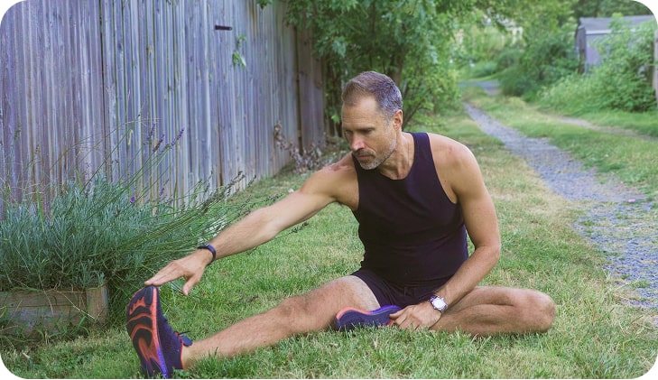 A man stretching on grass preparing for an outdoor run