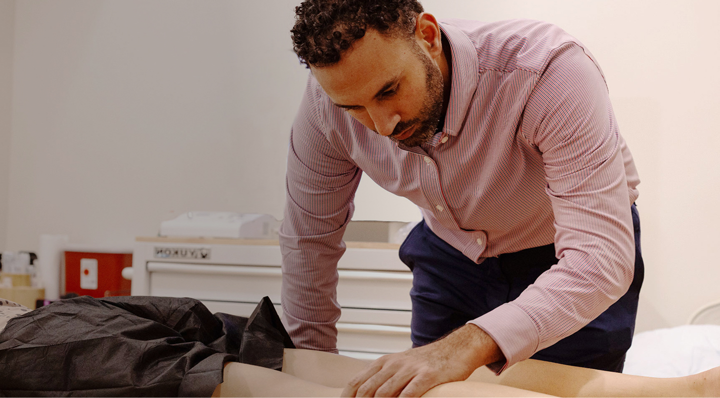 Dr. Stephen Matta conducts a physical exam on a male patient in a clinical setting.